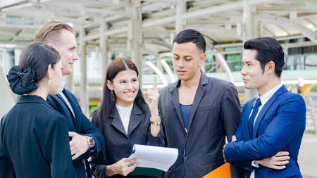 team of business multi internationality people smart man and woman talk and present the project work with the paper work on the hand  in good feeling at outdoor pedestrian walk way the city space modern buildingの写真素材