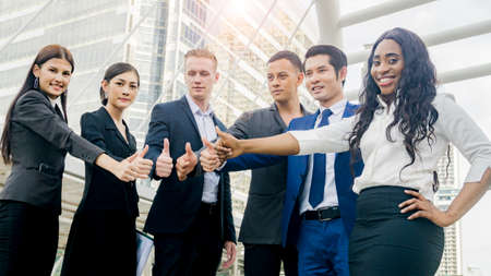 team of business people smart man and woman show hand thumb up in good feeling at outdoor pedestrian walk way.の写真素材