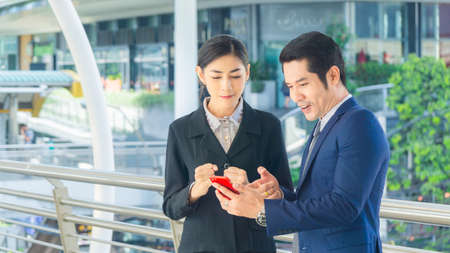 Excited business man and woman receiving good news on line in a smart phone outside on outdoorの写真素材