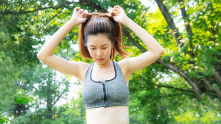 smart girl ties hair in fashion sportswear in garden morning, outdoor sports.の写真素材
