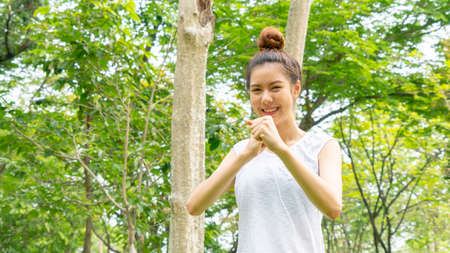 Asian cute healthy fit and firm slim teen lady warm up before workout for weight training or running at outdoor garden parkの写真素材