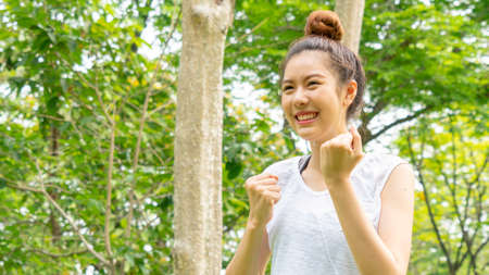 Asian cute healthy fit and firm slim teen lady warm up before workout for weight training or running at outdoor garden parkの写真素材