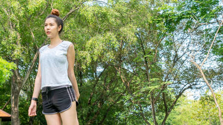 Asian cute healthy fit and firm slim teen lady warm up before workout for weight training or running at outdoor garden parkの写真素材