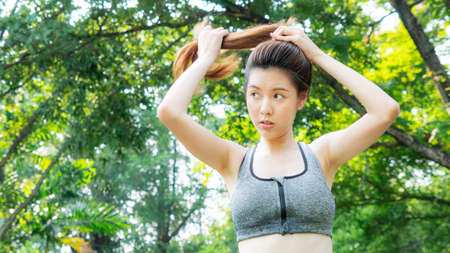 smart girl ties hair in fashion sportswear in garden morning, outdoor sports.の写真素材