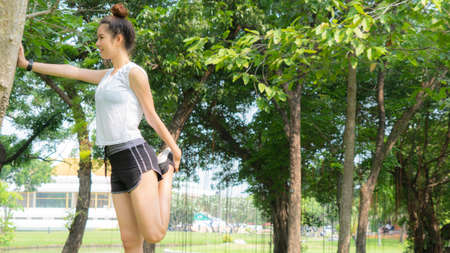 Asian cute healthy fit and firm slim teen lady warm up before workout for weight training or running at outdoor garden parkの写真素材