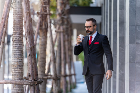 man in business suit holding cup of coffee. business lifestyle in coffee time at morning daylight.man feeling fresh and happy with confident of success.の写真素材