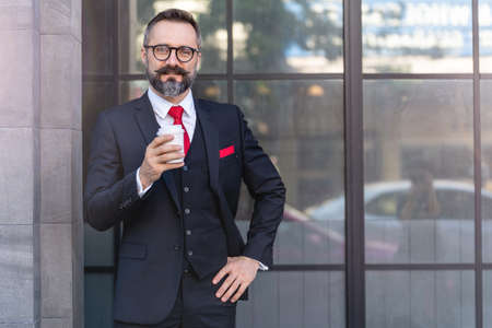 man in business suit holding cup of coffee. business lifestyle in coffee time at morning daylight.man feeling fresh and happy with confident of success.の写真素材