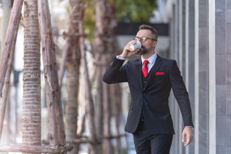 man in business suit holding cup of coffee. business lifestyle in coffee time at morning daylight.man feeling fresh and happy with confident of success.の写真素材