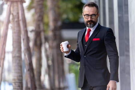 man in business suit holding cup of coffee. business lifestyle in coffee time at morning daylight.man feeling fresh and happy with confident of success.の写真素材