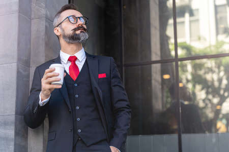 man in business suit holding cup of coffee. business lifestyle in coffee time at morning daylight.man feeling fresh and happy with confident of success.の写真素材