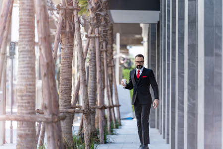 man in business suit holding cup of coffee. business lifestyle in coffee time at morning daylight.man feeling fresh and happy with confident of success.の写真素材