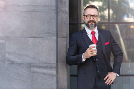 man in business suit holding cup of coffee. business lifestyle in coffee time at morning daylight.man feeling fresh and happy with confident of success.の写真素材