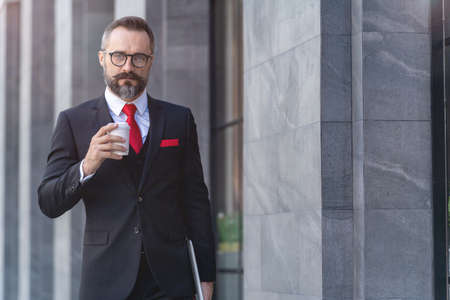 back of man in business suit walking and holding laptop notebook. business lifestyle in coffee time at morning daylight.の写真素材