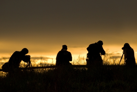 silhouette of photographer taking picture of landscape during sunsetの写真素材