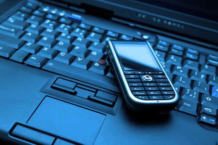 Blue-toned keyboard of high-end laptop and modern smartphone on it. RAW and Tiff also available on demand.の写真素材
