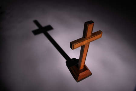 Christian wooden ñross in light beam. Shadow on background. Religious concept.の写真素材