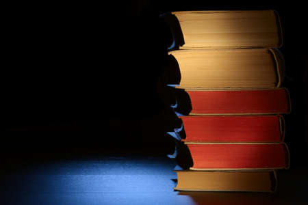 Old books on a table in moon light. Black backround. Copyspace composition.の写真素材