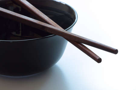 Wooden chopsticks on black dish. White background. Selective focus.の写真素材