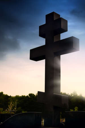 Cemetery. Cross on a cloudy sky background. Backlit scene.の写真素材