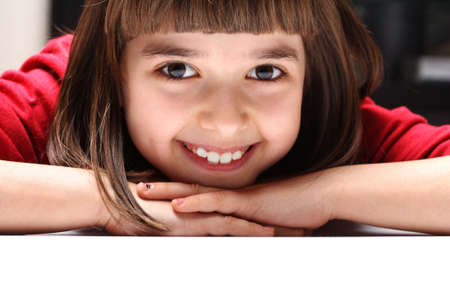 Girl 9 years old leaning on the table and laughsの写真素材