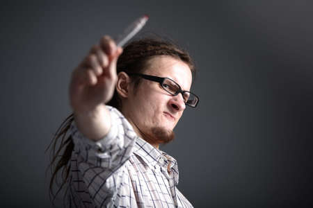 longhaired eccentric man in glasses makes a gesture of holding a markerの写真素材