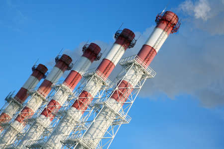 Five chimneys with steam on a blue sky background. Tilt view.の写真素材