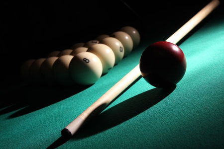 Balls pyramid with number 8 ball on a foreground, cue and red ball on a light beam.の写真素材