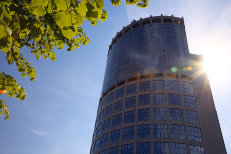 Modern skyscrapers on a background of blue sky and the branches of a tree with young foliage. The...
