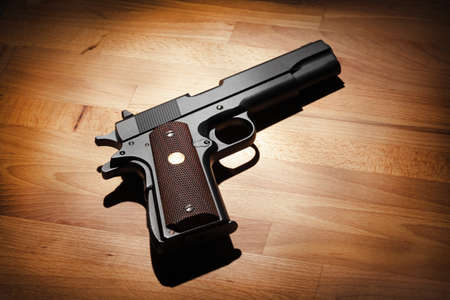 M1911 semi-automatic .45 caliber pistol on a wooden surface. Studio shotの写真素材