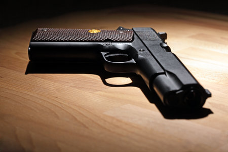 M1911 pistol on the wooden table. Shallow DOF.の写真素材