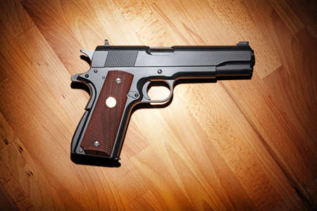 Semi-automatic M1911 Mark IV Series 80 .45 caliber pistol on the wooden table. の写真素材