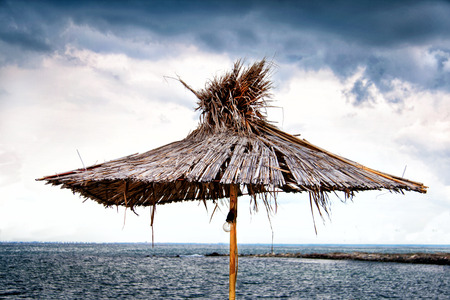 Beach umbrella of the reed on the background of cloudy sky and seaの写真素材
