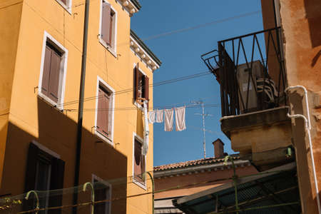 Venice, Italy - August 14, 2016: Old lady hangs freshly washed laundry to dry in the sun in Venice, Italy.のeditorial素材