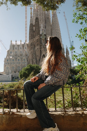 Young woman sitting by green pond at Sagrada Familiaの写真素材
