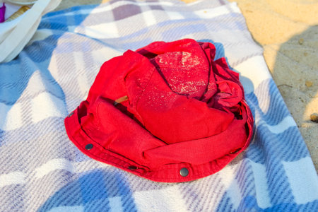 Bright red folded clothing item placed on striped blue and white beach towelの写真素材