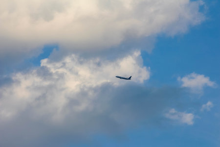 Small aircraft silhouette flying through dramatic cloudy sky with layers of white and gray cloudsの写真素材
