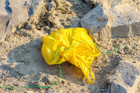 Discarded yellow material creating stark contrast against natural sandy beach environmentの写真素材