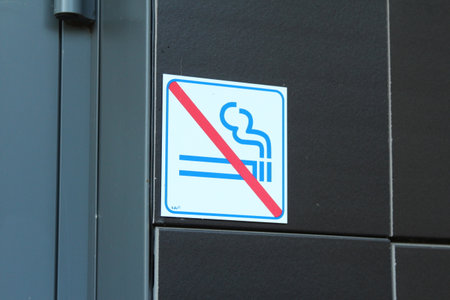 No smoking prohibition sign with crossed cigarette symbol mounted on dark building wall exteriorの写真素材