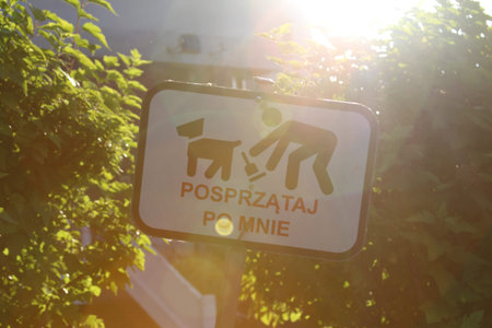 White dog prohibition sign with pictogram partially obscured by green foliage creating natural frame around regulatory signageの写真素材