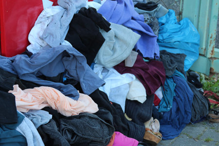 Pile of colorful mixed clothing and fabric scraps scattered on blue surfaceの写真素材