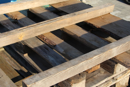 Stack of weathered wooden planks with metal strapping bands lying on concrete surfaceの写真素材