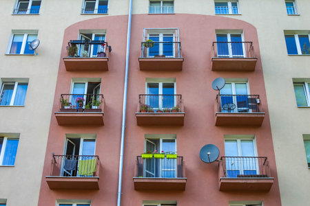 Multi-story residential building with blue balconies and traditional European architectural styleの写真素材
