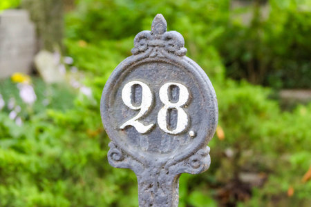 Ornate cemetery grave marker displaying number 98 with decorative metalwork and vintage styling in...
