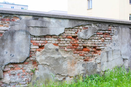 Weathered brick cemetery wall with peeling plaster revealing layered architectural decay and natural...