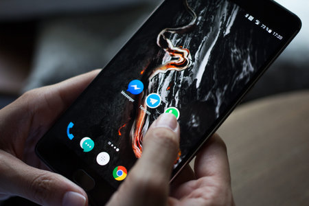 Moscow, RUSSIA - August 20th, 2017: Hands using smartphone One Plus 3T with icons of social media on...