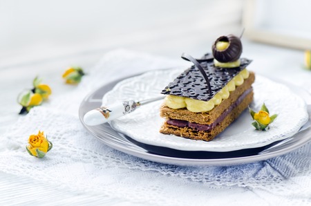 Millefeuille, french pastry with custard and chocolate on a white plate and wooden tableの写真素材