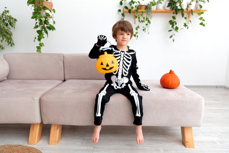 a child in a halloween costume sits with pumpkinの写真素材