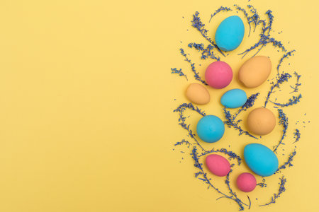Flat lay Easter pastel colored eggs on yellow backgroundの写真素材