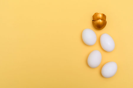 White and gold eggs on the yellow background. creative flatlay