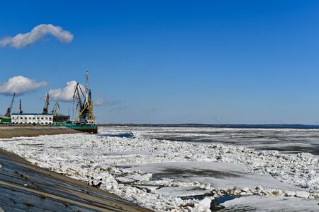 SURGUT, KHANTY - MANSIYSKIY AVTONOMNYY OKRUG, ROSSIYA - MAY 5, 2019:  Port part of the Ob Quay. Ice drift. The boys approach the river, they are attracted by the cold blocks of ice.のeditorial素材